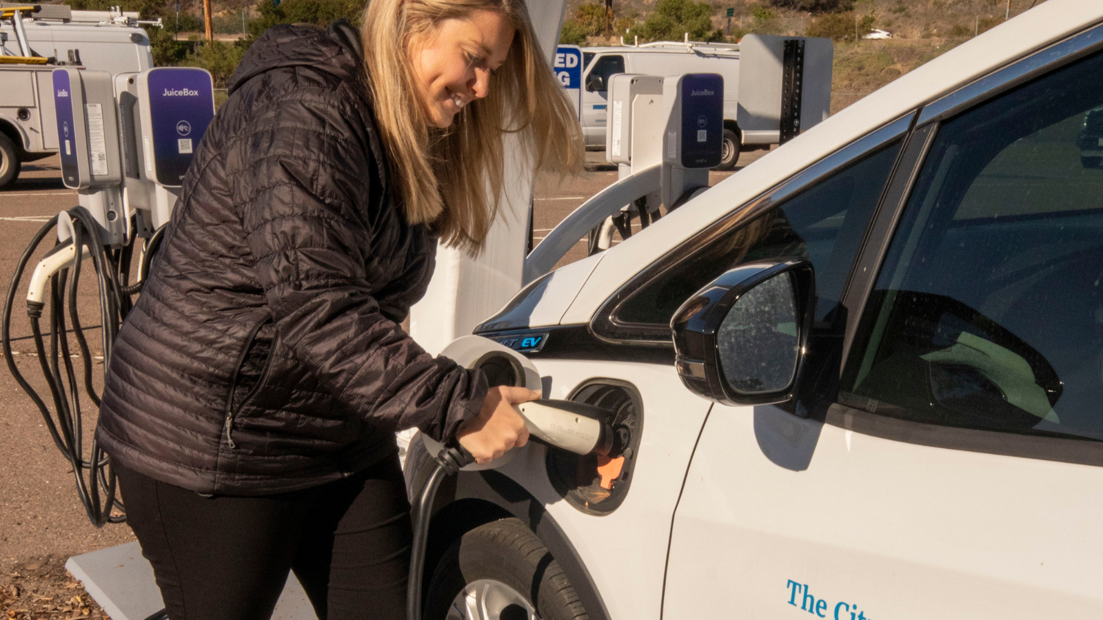 persons plugging a charger into an electric vehicle 
