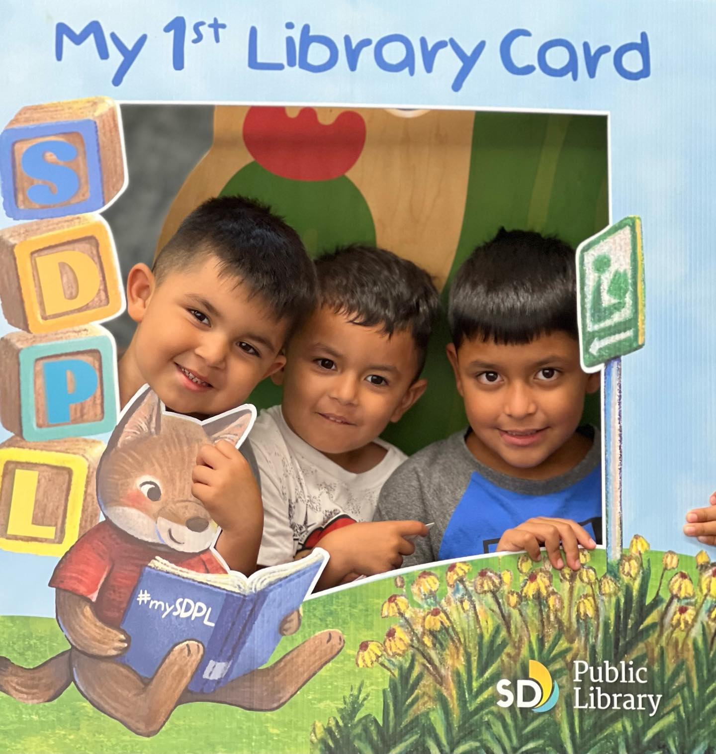 three young boys posing with a My 1st library card photo frame.