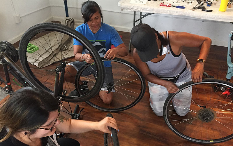A group of ladies working together to repair bicycles