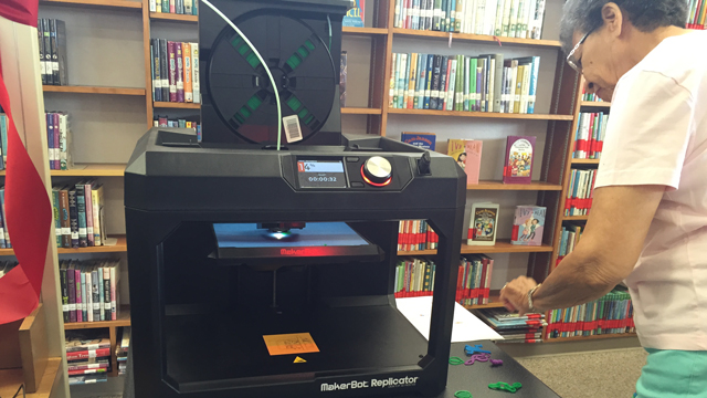 A volunteer assists with new 3D printing program at the Clairemont Library