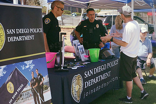 Two police officers speaking to a candidate at a recruiting event
