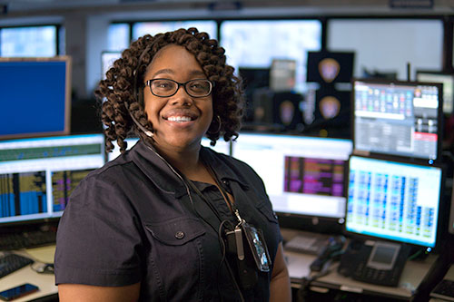 San Diego Police dispatcher smiling in front of her workstation