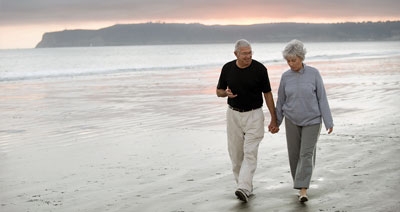 A senior couple walking on the beach at sunset