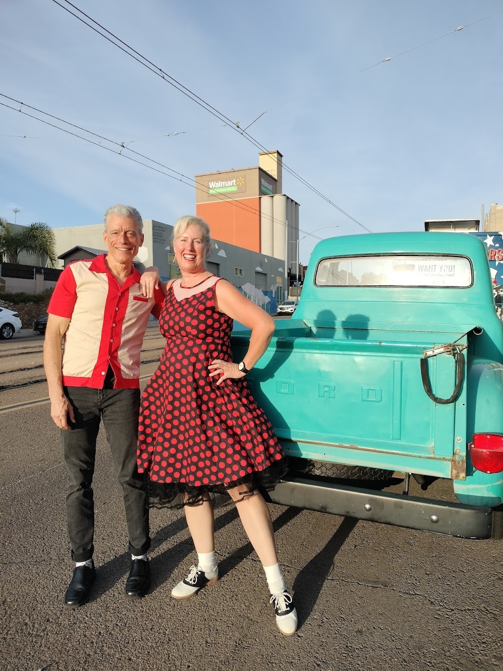 Couple in swing dancing outfits posing in front of a vintage car