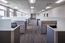 inside of an office with the aisle down the middle and two rows of cubicles lined up