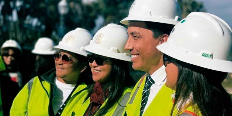 Mayor Todd Gloria wearing a hard hat posing with construction representatives