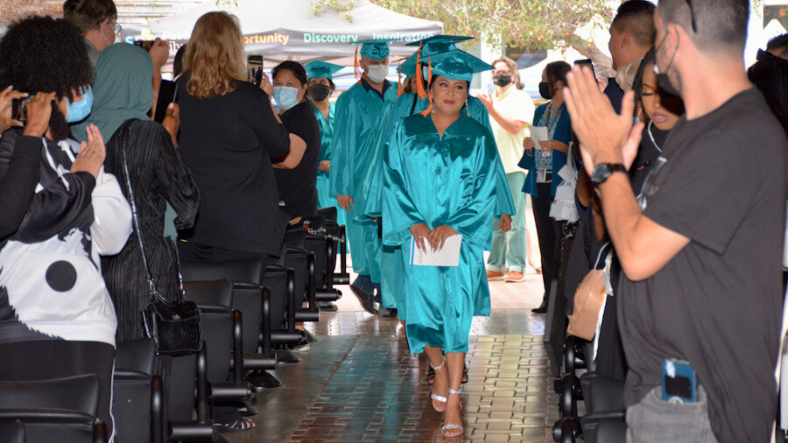 career online high school graduates walking down an aisle&#44; surrounded by cheering people