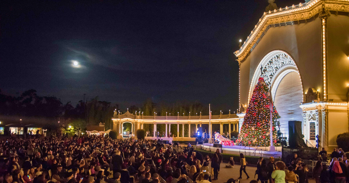 people doing a performance on the stage during december nights event in front of a christmas tree. 