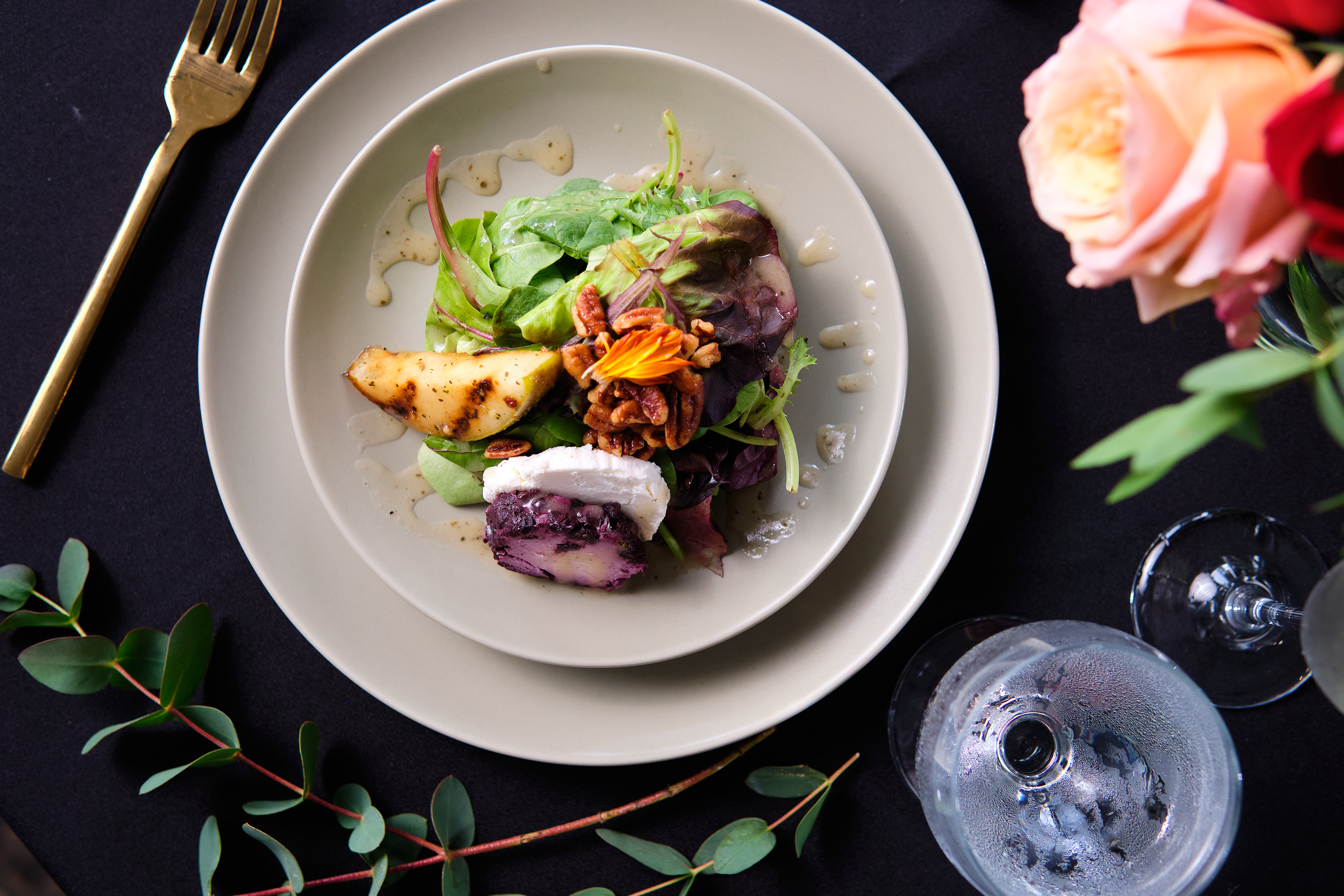 Plate of food surrounded by rose, leaves, and fork