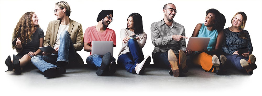 Diverse group of people using computer devices while sitting on the floor