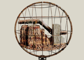 Image of a rusty pipe and rocks in a circular metal cage by artist Oscar Romo