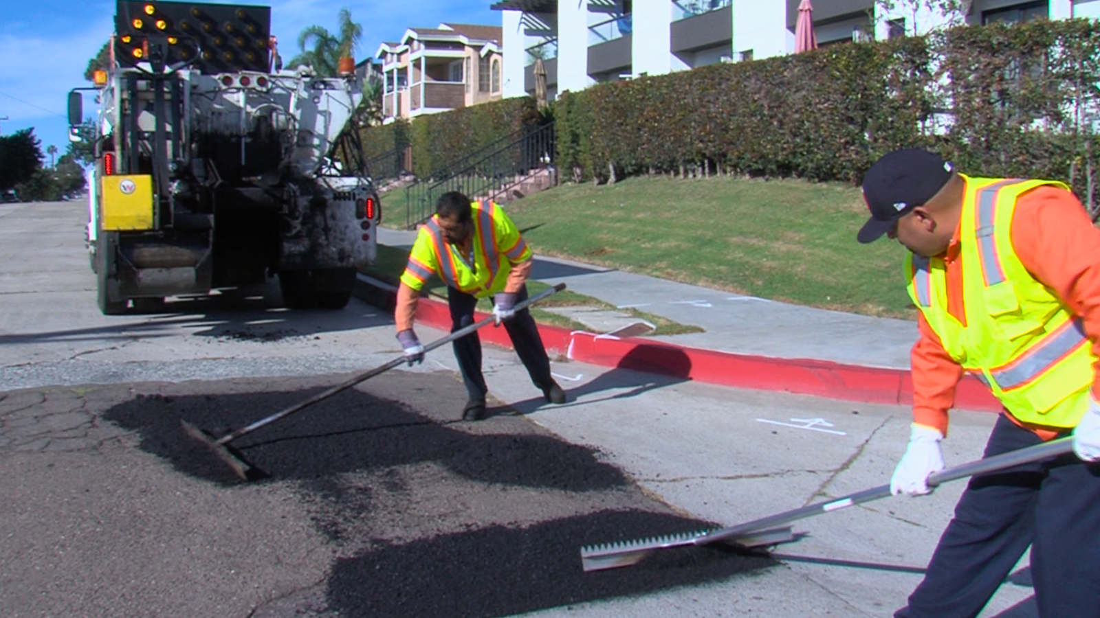Two city workers filling in pot holes