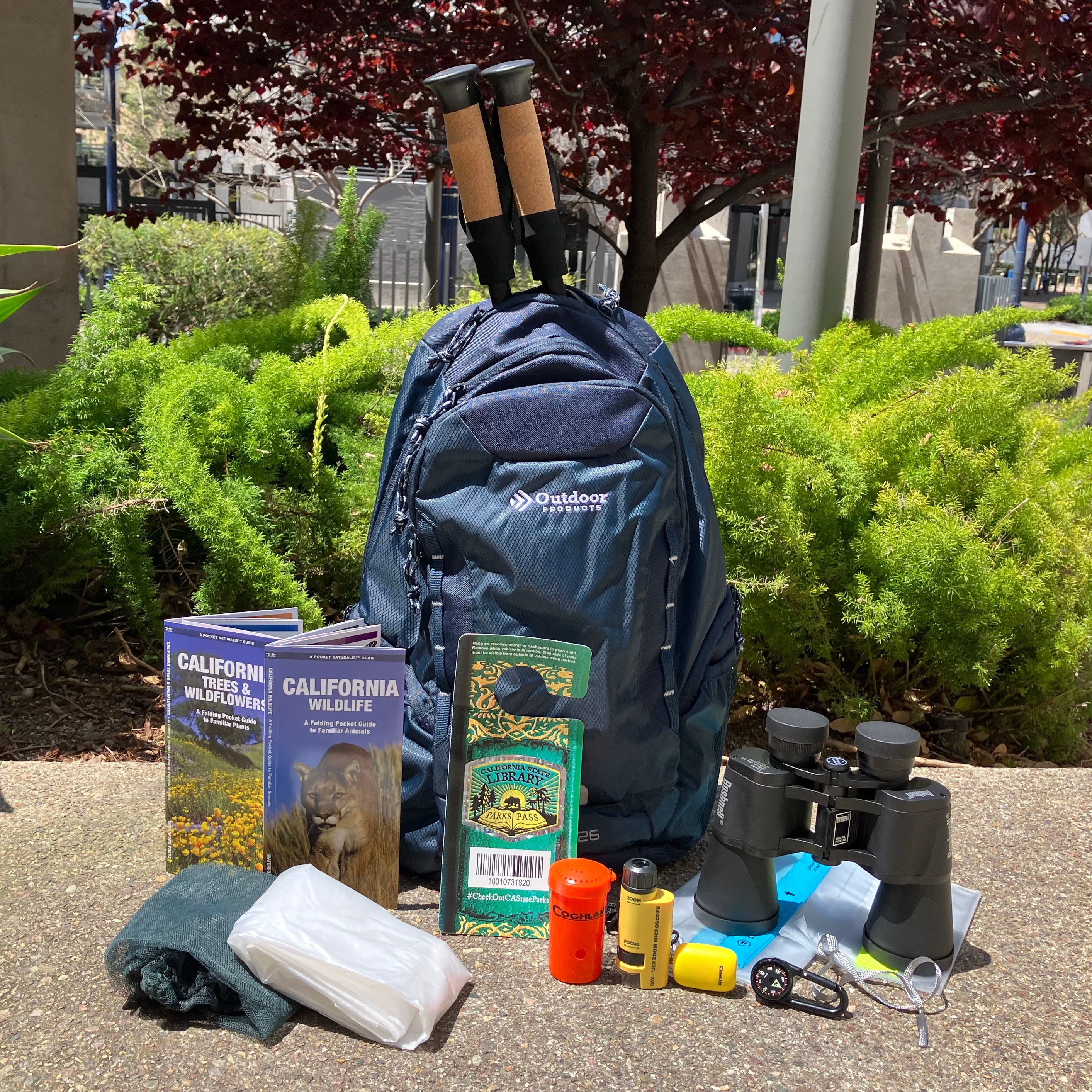 Backpack next to parks pass, binoculars, flashlight, emergency gear and more