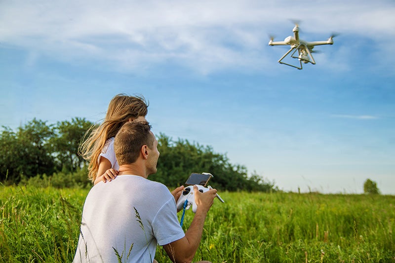 A man flies a drone while a little girl watches