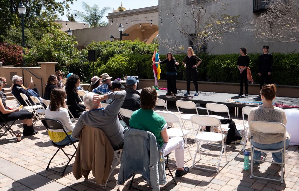 4 performers wearing black on stage, in front of an audience 