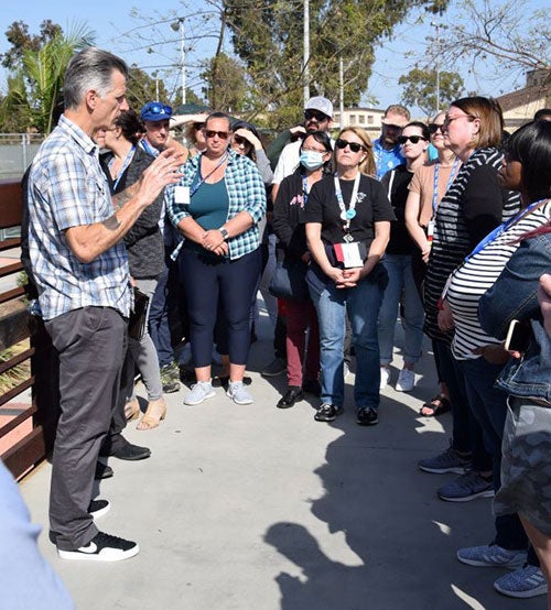 A person speaks in front of a crowd as they are standing on a bridge
