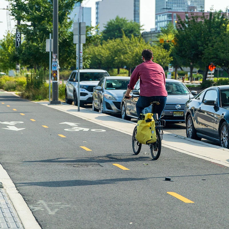 Bicyclist on a bike path next to parked cars
