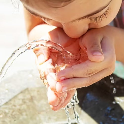 child drinking from drinking fountain