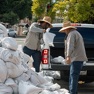 Two workers loading sandbags onto a truck
