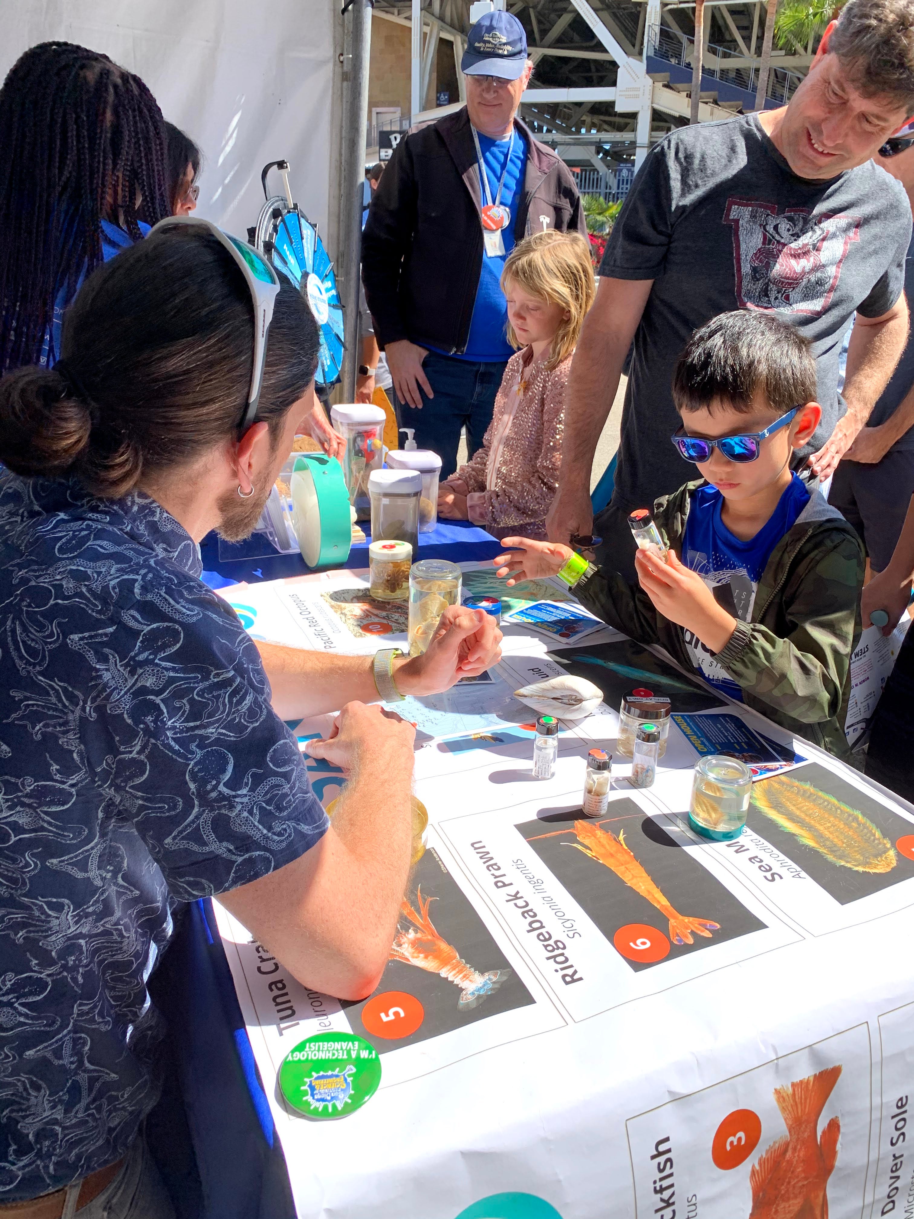 Marine Biologist showing a vial of invertebrates to a visitor.