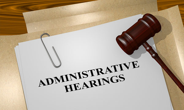 A gavel on top of a paper with the title Administrative Hearings