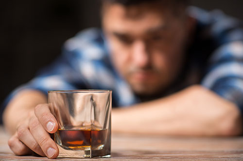 Man addicted to alcohol with glass of liquor in his hand