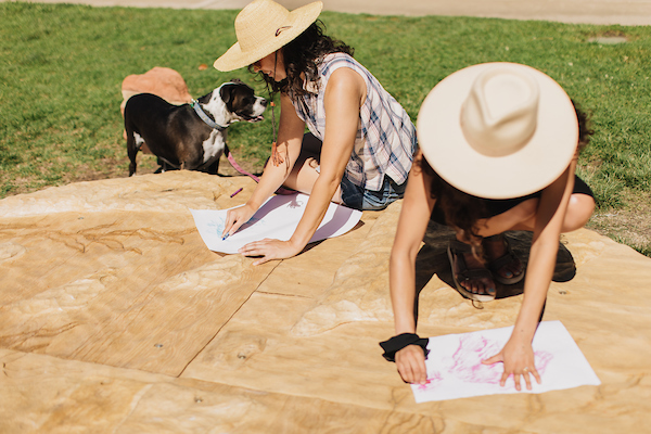 Artists drawing on paper while sitting on a wooden circular platform