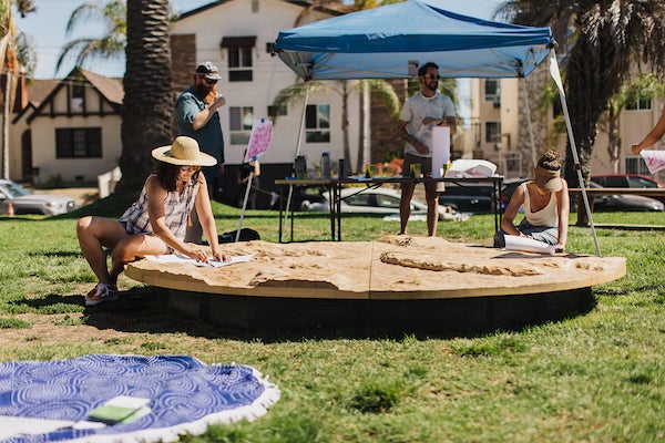 Artists constructing an artistic piece on a wooden circular platform