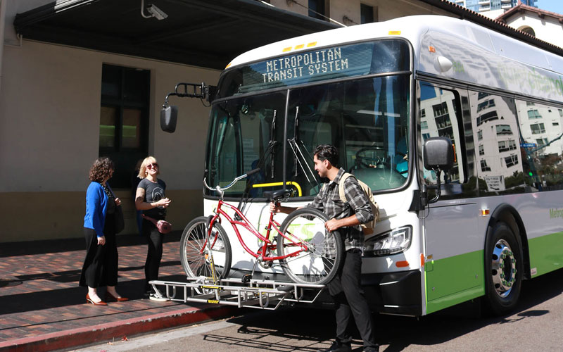 Bus rider placing bike on rack mount in front of bus