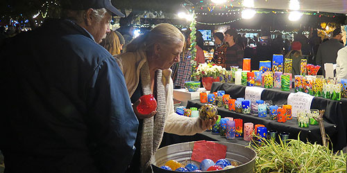 December Nights attendees browsing holiday candles that are sold by a vendor