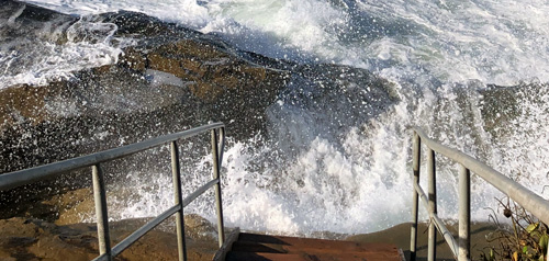 Waves crashing against rocks at the bottom of stairs