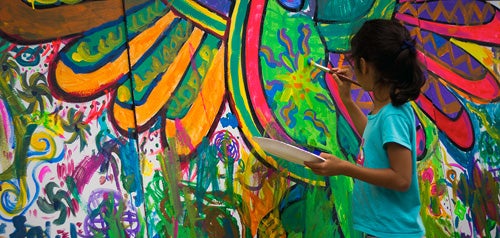 Young girl painting a mural on a wall