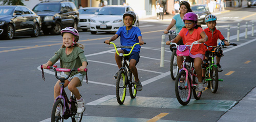 Children riding bikes on a bike lane in a downtown street