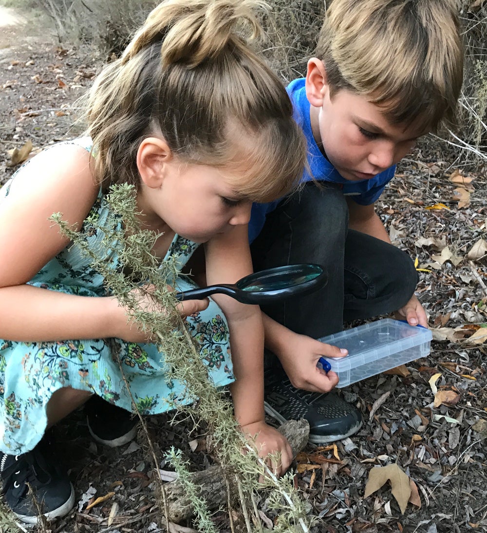 Photo of boy and girl using magnifying glass