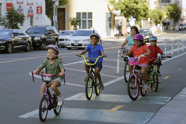 Children riding bikes on a bike lane in a downtown street