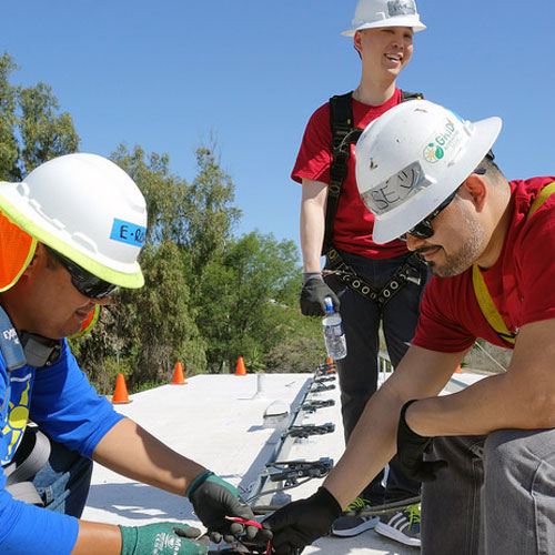 People with hard hats installing solar panels