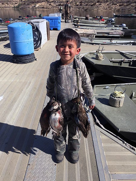 Youth displaying waterfowl caught at reservoir lake