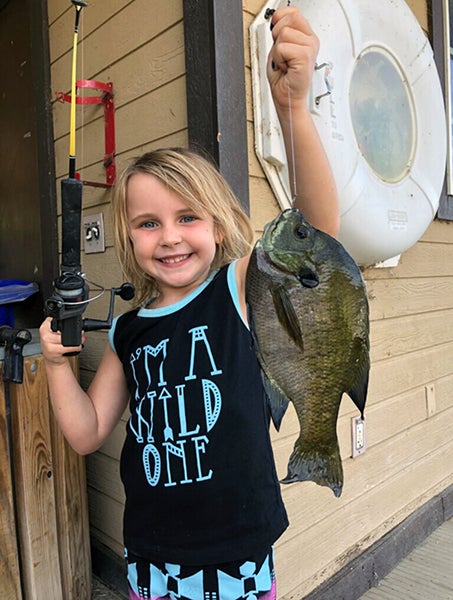 Young angler displaying fish caught at reservoir lake