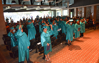 Graduates standing up with hands on caps