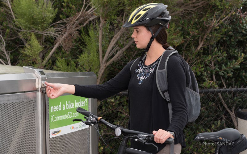 Young lady putting her bike inside a bike locker