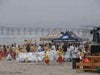 People on the beach around tents with ocean in the background