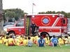 Officer talking with kids sitting down with San Diego Medical Enterprise bus