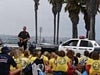 Officer talking with kids sitting down with a Police Dog car