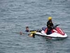 An officer on a rescue Water Motorbike helping two kids