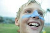 A young boy laughing with blue sunscreen on his nose