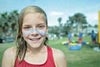 A girl smiling with blue sunscreen on her cheeks