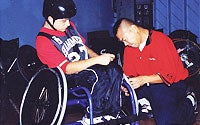 Photo of Volunteer Assisting Boy in Wheelchair