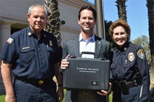 Photo of Councilmember Kersey presenting the Police Department with 32 donated AEDs
