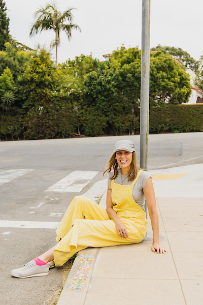 Margaret Noble sitting on a curb edge decorated with art