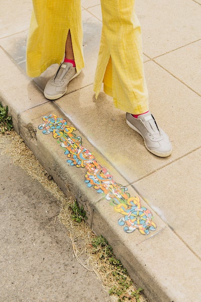 Margaret Noble sitting on a curb edge decorated with art